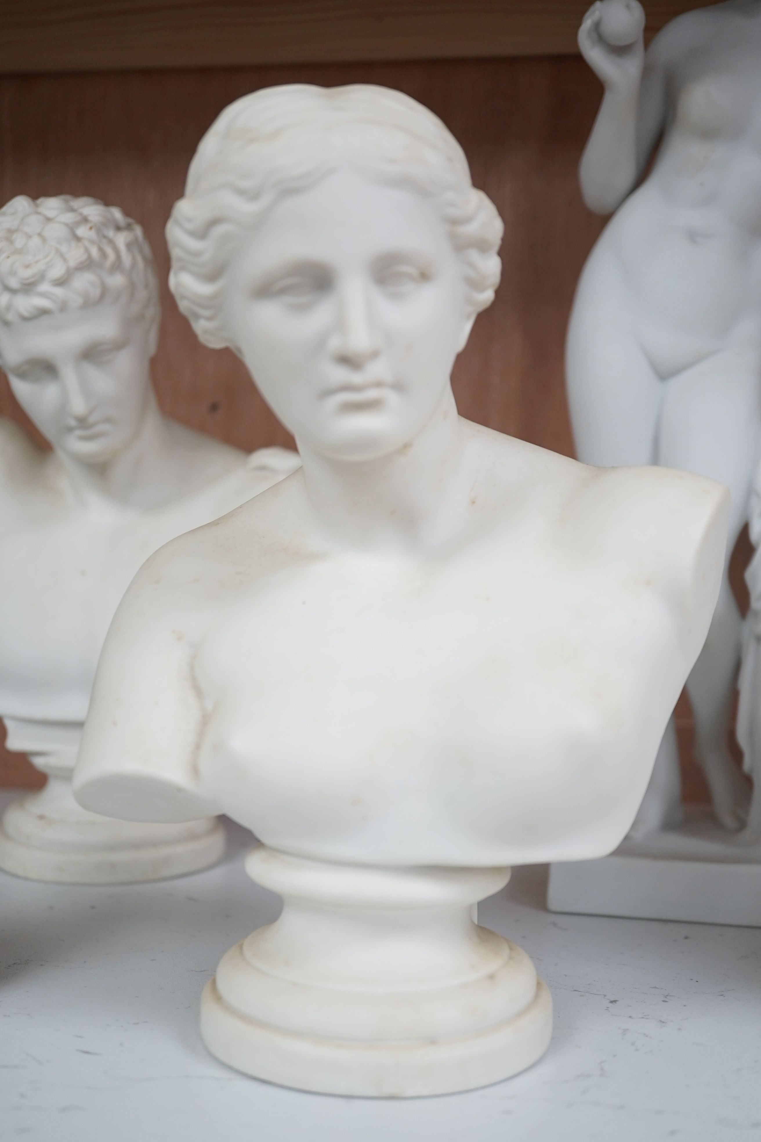 Two parian busts, a classical figure, another seated figure and a miniature three graces group, to include Gustavsberg - tallest 33cm